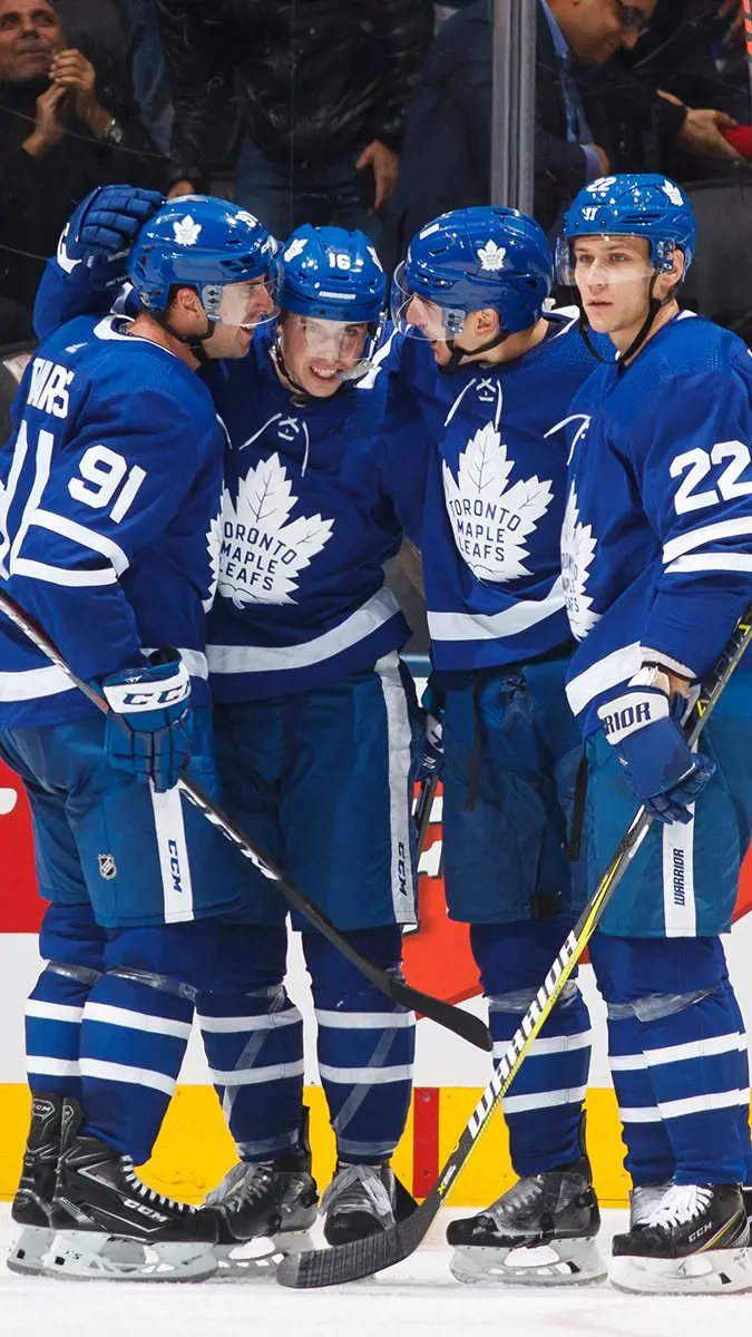 The Toronto Maple Leafs discussing on the rink wearing blue jersey